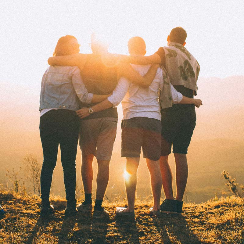Friends standing together looking at a sunrise